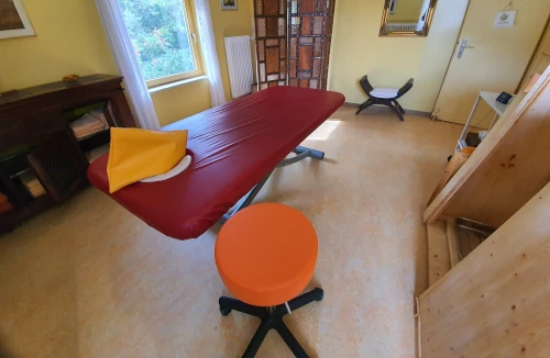 Blick in einen Massageraum im AUM Kurzentrum mit Hocker, Massageliege und offener Saunatür