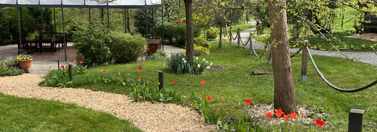 Foto zeigt kleinen Weg mit bluehenden Blumen zum Pavillon des Gartens