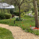 Foto zeigt kleinen Weg mit bluehenden Blumen zum Pavillon des Gartens